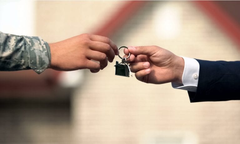 Military soldier being handed key by realtor for new home