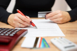 Woman checking a paper representing a personal loan while holding a credit card.