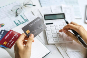 Hand of woman calculating multiple credit card bills.