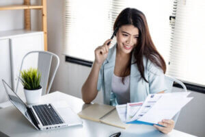 Young woman holding bills with smile happily after consolidating debt.